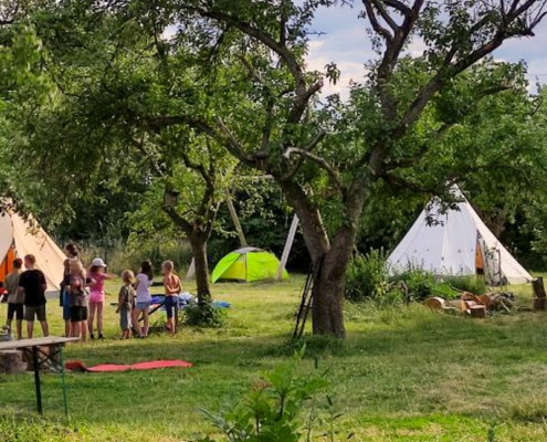 Sommercamp mit Zelten und Gruppe beim Bogenschießen